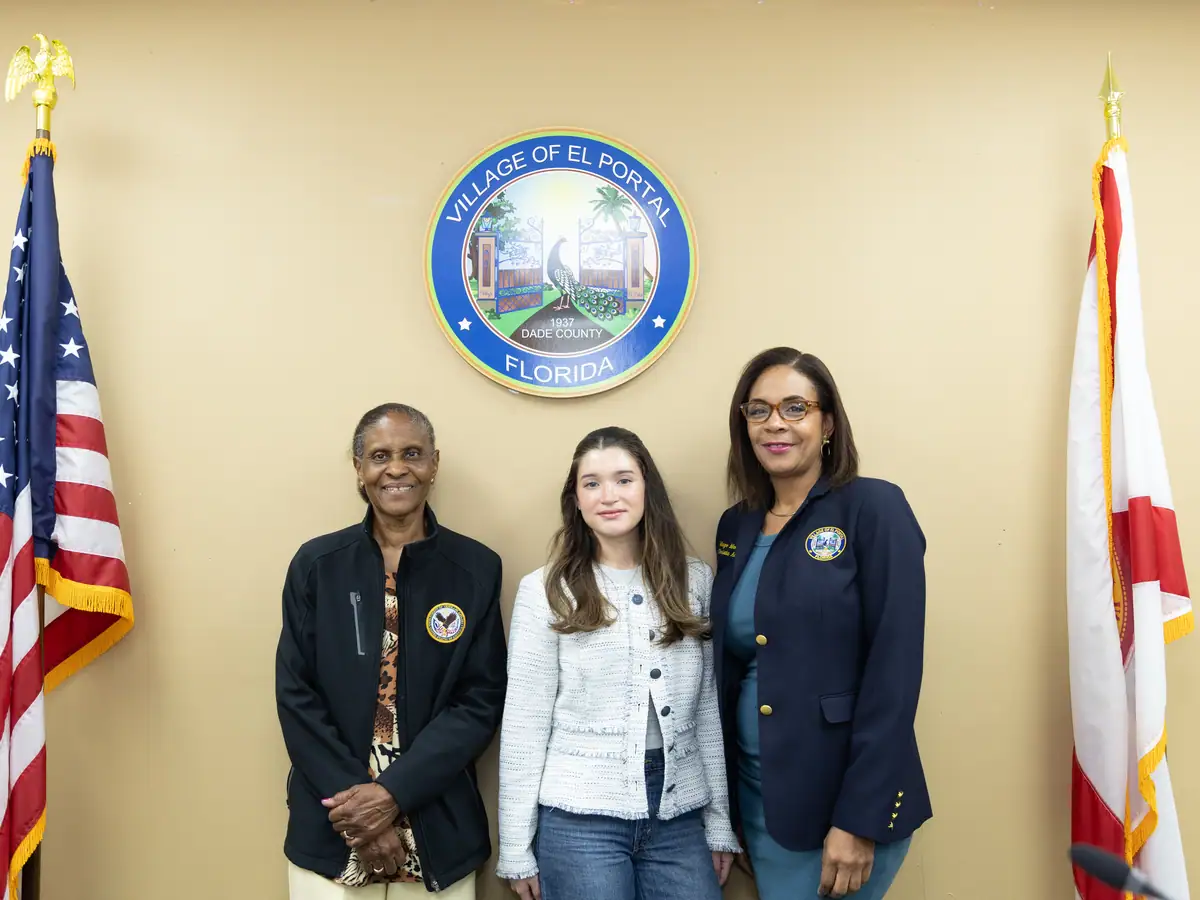 A student stands with El Portal leadership beneath the village seal.